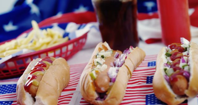 Hot dogs with various toppings are presented on a table adorned with an American flag motif, evoking a festive Fourth of July or Memorial Day barbecue atmosphere. Such settings are emblematic of American culture and celebrations, often associated with national holidays and summertime gatherings.