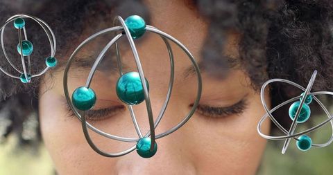 Resting woman with floating metal gyros and teal reflective orbs, surreal portrait headshot