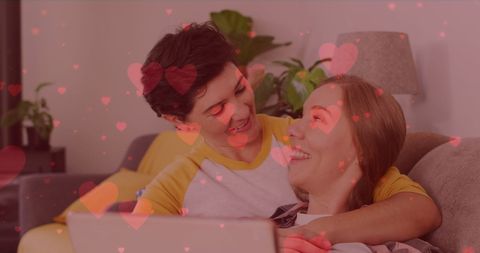 Loving Female Couple Embracing with Heart Overlays at Home