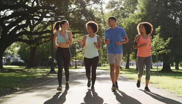Group jogging in sunlit park promoting fitness, friendship, diversity and active lifestyle