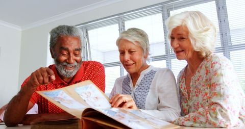 Senior group enjoying photo album in nursing home interior