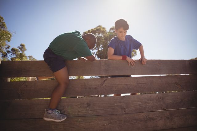 Kids climbing wooden wall during obstacle course in boot camp