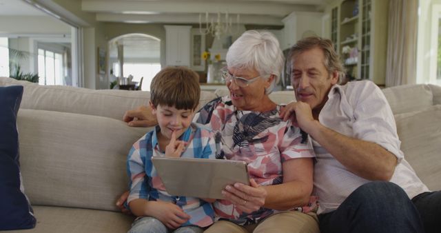 Grandparents and Grandchild Using Tablet Sitting on Couch in Living Room - Download Free Stock Images Pikwizard.com