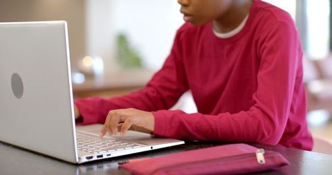 African American Boy Typing on Laptop at Kitchen Table with Zippered Pencil Pouch