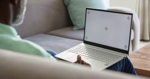 Mature African American Man Working on Laptop with Target Markers on Blank Screen at Home