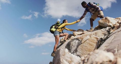 Helping hand: couple climbing rocky outcrop showing teamwork and outdoor adventure