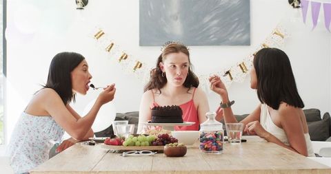 Three Women Celebrating Birthday with Cake in Modern Dining Room