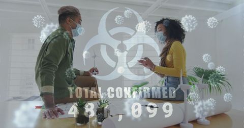 Two Colleagues Discussing in Office with Covid Statistics Overlay