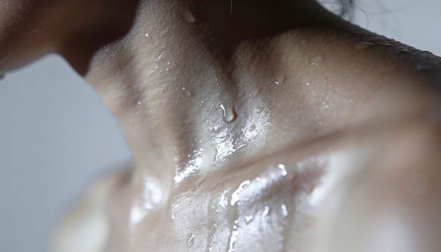 Glistening female neck and collarbone showing water droplets and skin texture