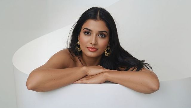 Elegant woman resting on white podium wearing gold hoops