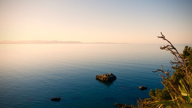 Tranquil Coastal Sunset with Calm Waters and Distant Mountains - Download Free Stock Photos Pikwizard.com