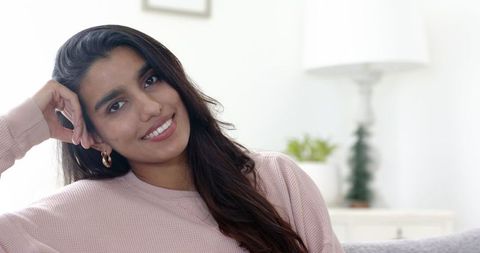 Relaxed indian woman smiling at home in cozy living room