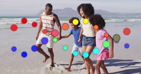 Family of four walking hand in hand splashing surf on sunny sandy beach with colorful stickers