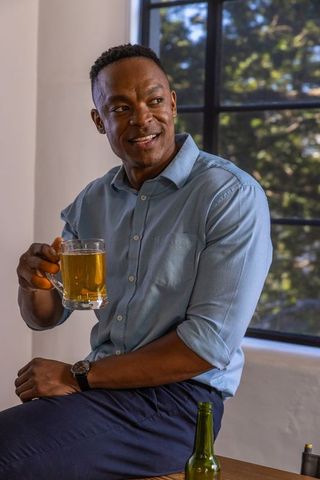 Casual african american man enjoying beer by window