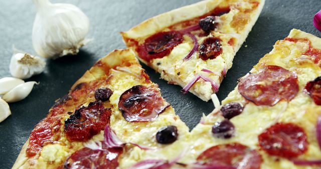 Pepperoni pizza slices with melted cheese, red onion, and olives, ideal for food blogs, recipe websites, and restaurant marketing material.