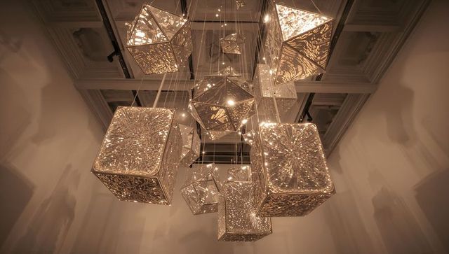 Illuminated geometric sculptures hanging in a contemporary art space