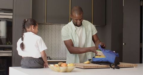 Father prepares lunch with daughter in kitchen going to school