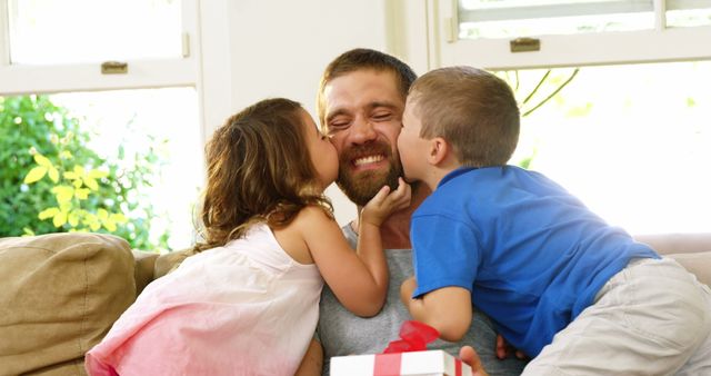 A middle-aged Caucasian man is joyfully receiving kisses on the cheeks from a young girl and boy, with copy space. Capturing a moment of affection, the image reflects a warm family dynamic and the love between a father and his children.