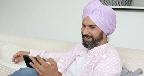 Turban-Wearing Man Relaxing with Tablet at Home on Couch