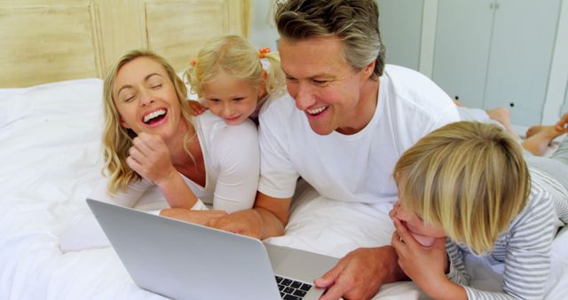 Happy family bonding while lying on bed and watching laptop together - Download Free Stock Images Pikwizard.com