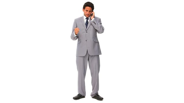 Elegantly dressed businessman in suit getting nervous during phone call against white background. Ideal for demonstrating business stress, communication challenges, or emotional dynamics in corporate environments.