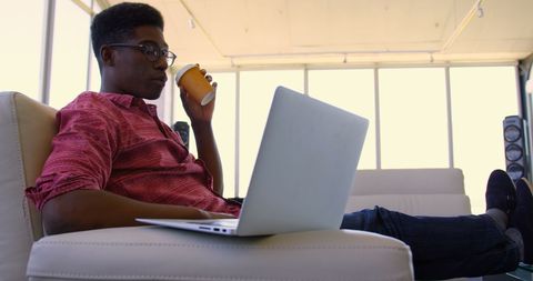 Young Man Working on Laptop and Drinking Coffee in Modern Office - Download Free Stock Images Pikwizard.com