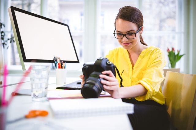 Happy young female executive looking at camera in creative office