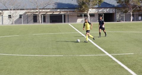 Teen soccer players practicing dribbling and defense outdoors