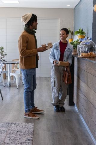 African american couple sharing takeaway coffee and pastry at cozy modern cafe counter
