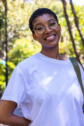 Smiling african american woman wearing glasses and white tee in sunny park
