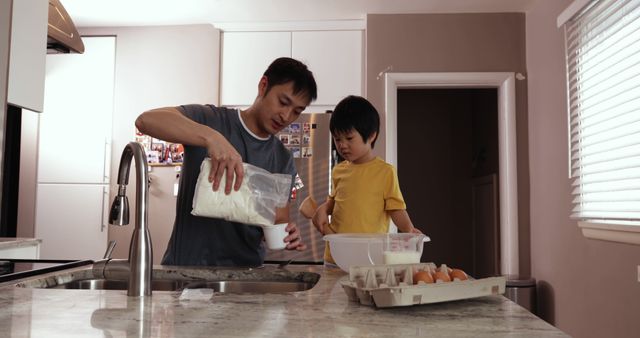 Asian father and son share a bonding experience by preparing a meal together in their home kitchen. This can be used for content focusing on family relationships, healthy cooking, parenting activities, and promoting family togetherness. It is perfect for advertisements or articles about family-oriented products, cooking tutorials, or father-son relationship themes.