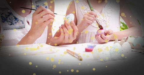 Mother and daughter painting colorful Easter eggs on sunny garden patio