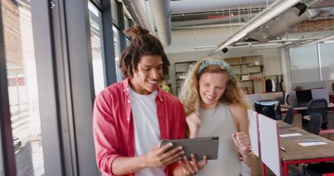 Joyful Colleagues Celebrating Success in Modern Office with Tablet