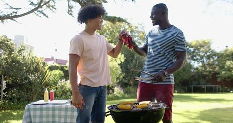 Friends Enjoying Barbecue and Drinks in Sunny Backyard