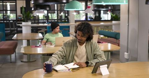 Young professionals working in coworking space writing notes and using tablet