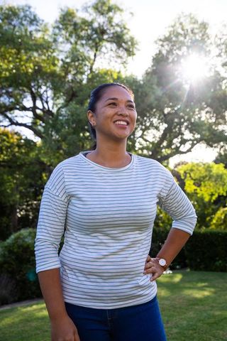 Asian Woman Smiling in Sunlit Garden Embracing Tranquility