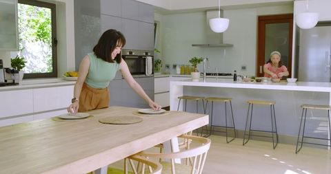 Mother and Daughter Setting Table in Modern Home Kitchen
