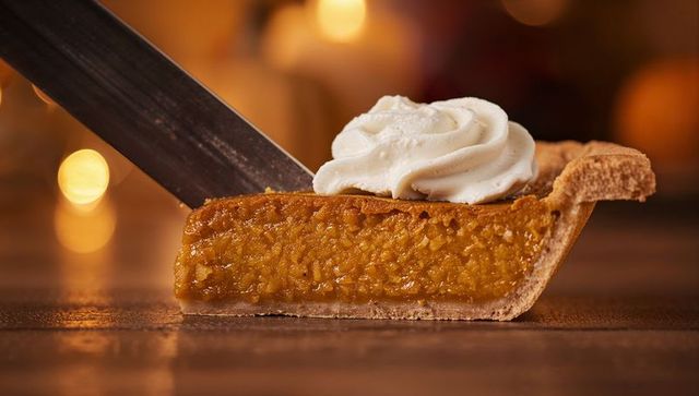 Lifting pumpkin pie slice on spatula with whipped cream and golden filling