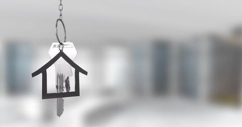 Hanging silver keys with house-shaped key tag over blurred modern interior