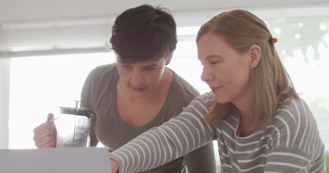 Caucasian lesbian couple talking to each other while using laptop at home. lgbt relationship and lifestyle concept