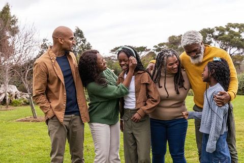 Multigenerational african american family laughing and embracing in park greenspace