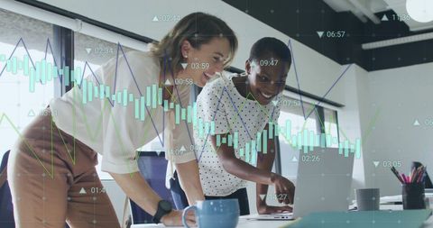 Two Women Analyzing Financial Data on Laptop in Modern Office