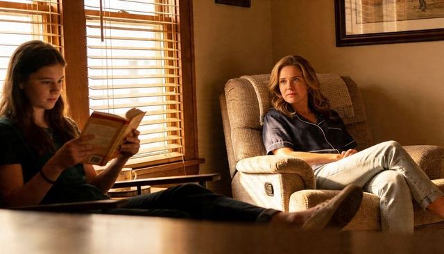 Mother relaxing in recliner watching daughter reading by sunlit window