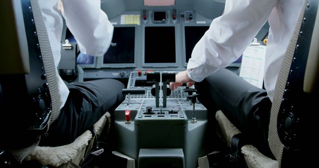 Caucasian pilots operate controls in a cockpit, with copy space. Precision and teamwork are essential in this high-pressure aviation environment.