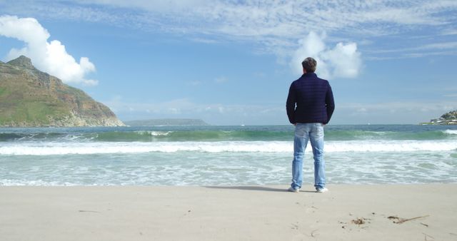 Man Standing on Beach Looking at Sea with Rocky Island in the Distance - Download Free Stock Images Pikwizard.com