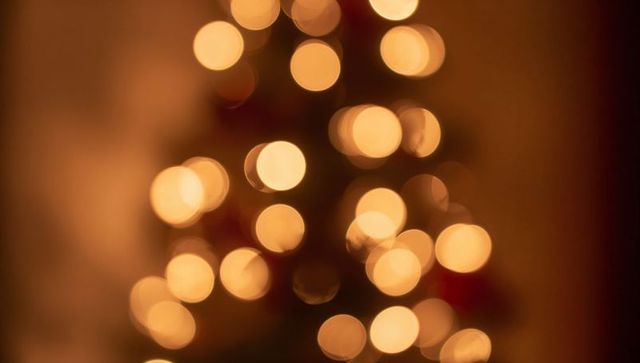 Glowing golden bokeh lights forming triangular tree silhouette warm festive abstract
