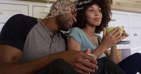 Couple leaning on entryway with mugs and calm expressions