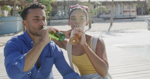 Biracial Couple Enjoying Drinks on Sunny Beach Pier