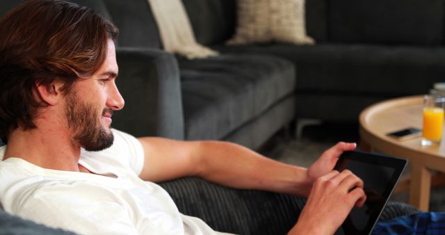 Man Smiling While Using Tablet on Couch at Home - Download Free Stock Images Pikwizard.com