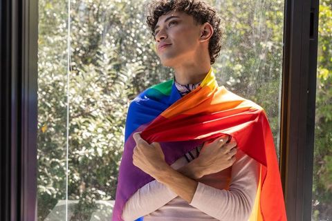 Youthful man embracing lgbtq pride indoors with radiant light